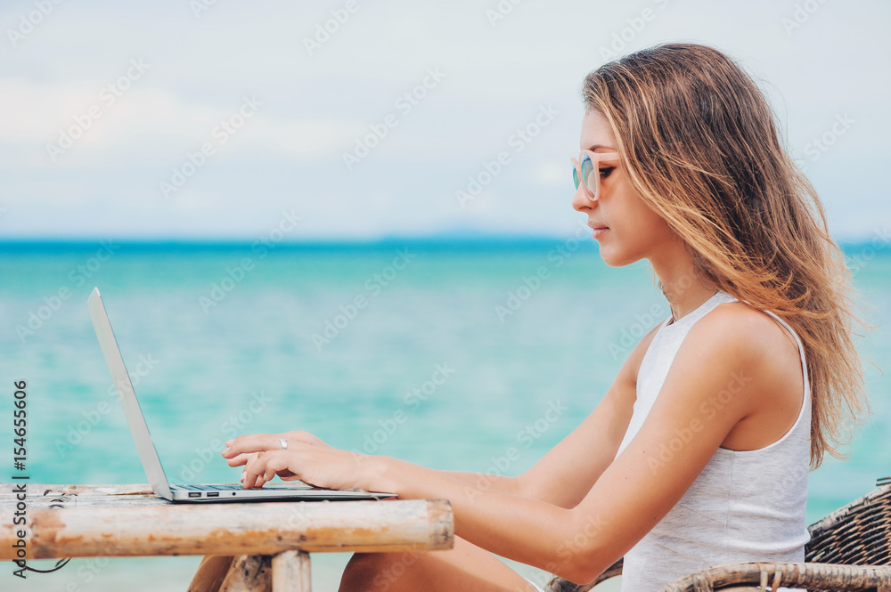 Young sexy woman using laptop on the beach. Freelance work