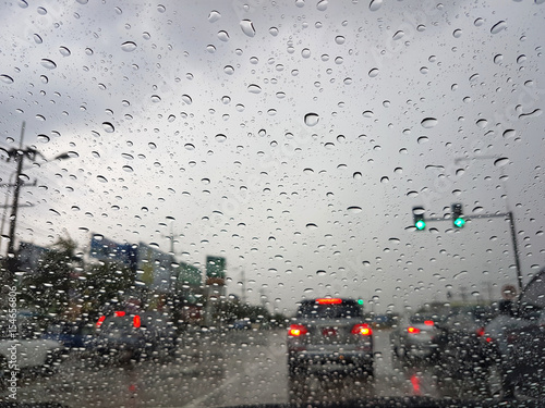 POV front driving a car or vehicle in the rain on the road with green traffic lights
