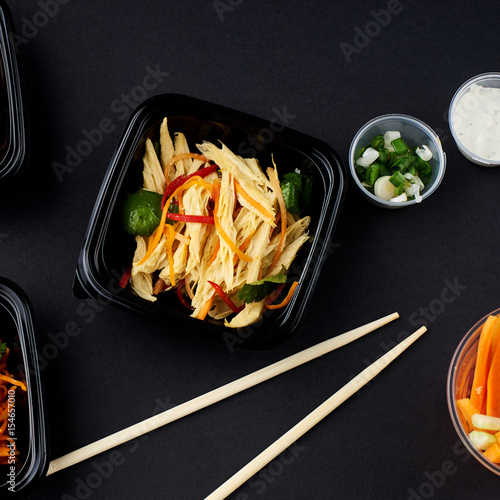 Korean cuisine. Set of salads on black background. Asparagus, korean carrot, kaktugi, fresh vegetable sticks and green onion. photo