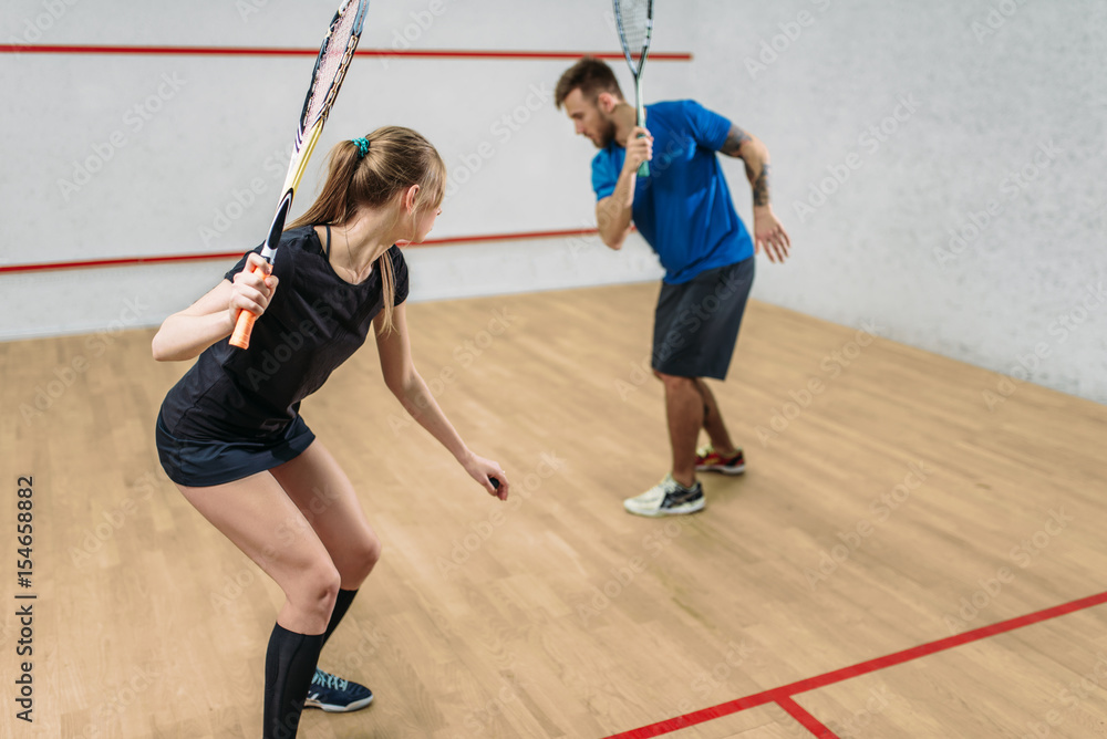 Couple with squash rackets, indoor training club