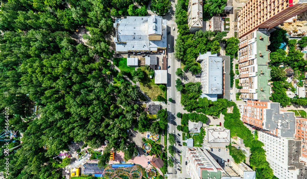 Fototapeta premium Aerial city view with crossroads and roads, houses, buildings, parks and parking lots, bridges. Helicopter drone shot. Wide Panoramic image.