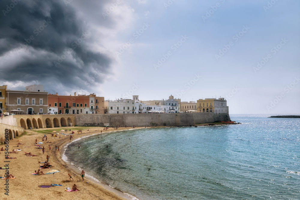 Beach and old town of Gallipoli under clouds of brewing thunderstorm, selective focus, Puglia, Italy