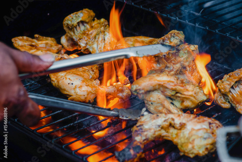 Chef cooking jerk barbecue BBQ chicken on the grill hand turning food photo