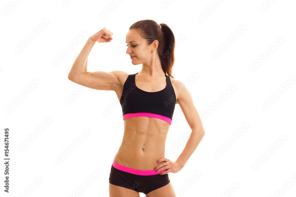 Slim young girl in sportswear looks at his muscle on hand Slim young girl in sportswear looks at his muscle on hand
