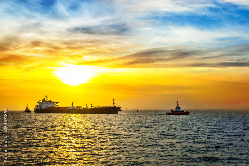 Sun setting at the sea with tanker ship.