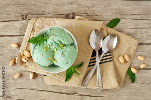 Bowl of pistachio ice cream, overhead still life on a wooden background