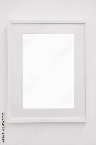 Closeup vertical blank white frame on white wall, decoration concept