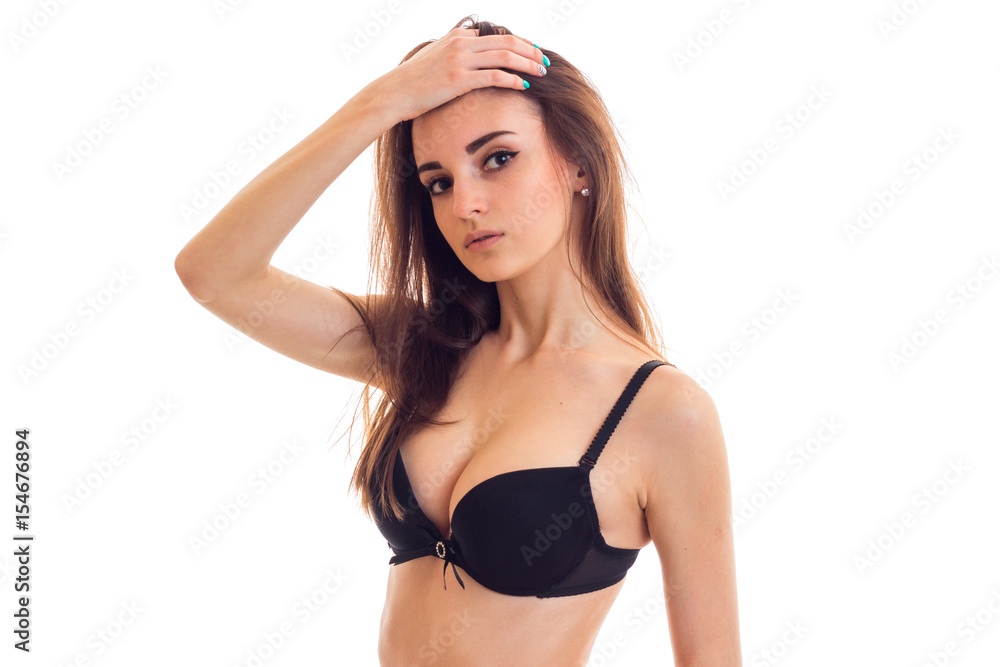 Portrait of a beautiful young girl with beautiful natural breasts in a  black bra which has raised her hand to head and looks into the camera Stock  Photo