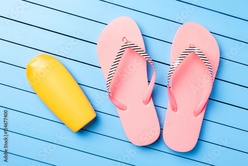 Pink flip flops on blue wooden table. Summer background