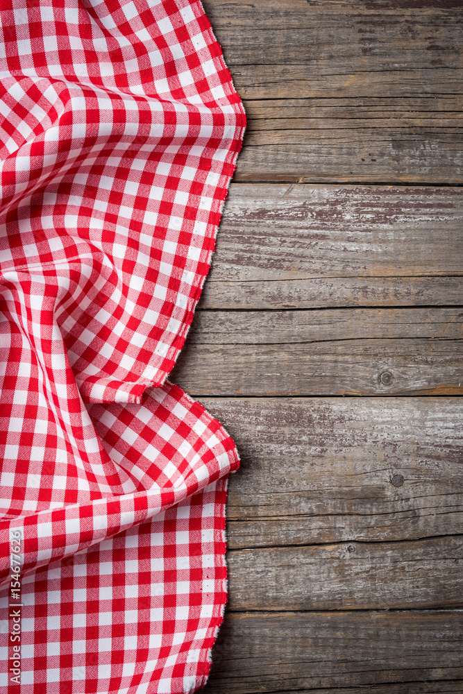 Red folded tablecloth on an old wooden table. Close up Red folded tablecloth on an old wooden table. Close up