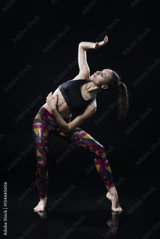 The girl dances on the floor covered with water on a black background