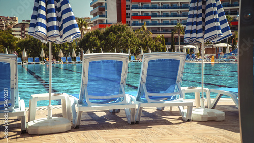 Sun loungers are near the pool. Blue  azure water. Light ripples on the surface of blue water. The concept of a luxury holiday for children and parents in a tropical resort during the holidays.