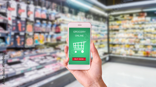 woman hand  holding mobile with grocery online on screen with blur supermarket background
