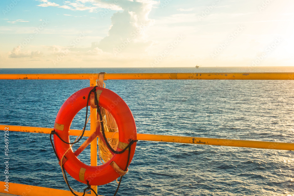 Safety equipment, Life buoy or rescue buoy hanging on handrail with sea sky background in sun set time