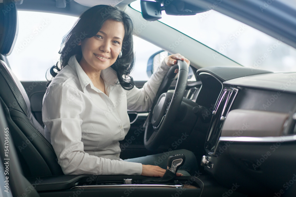 Beautiful mature woman checking out new cars at the dealership Beautiful mature woman checking out new cars at the dealership