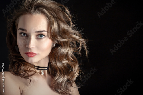 luxury woman with curly long hair on black background