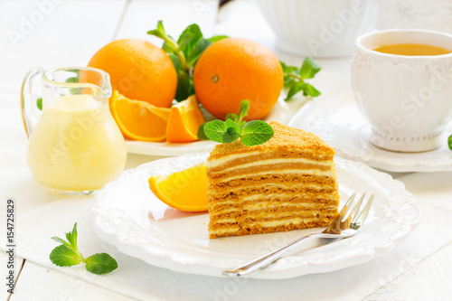Homemade honey cake with orange cream on a white plate.