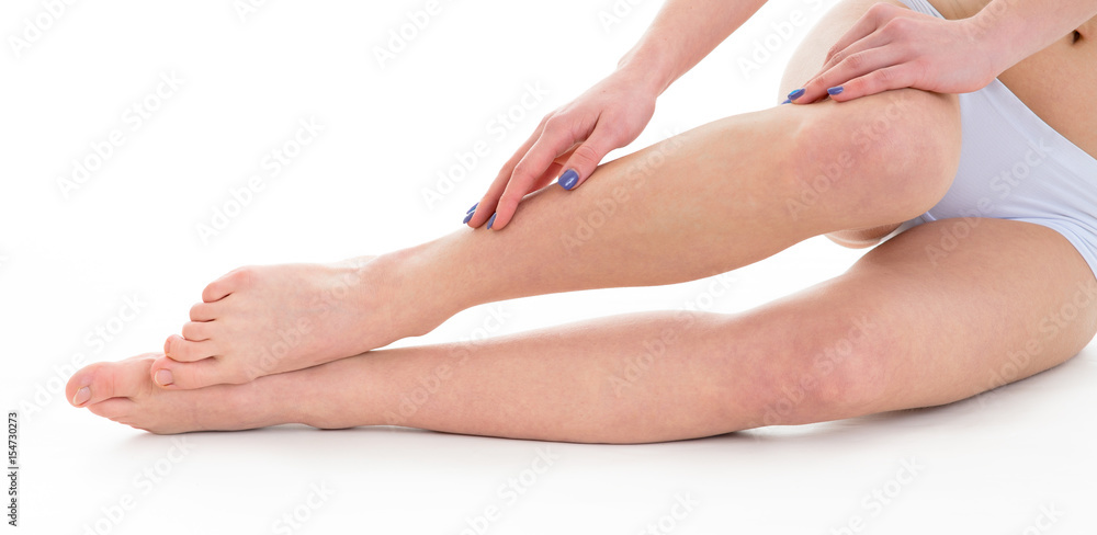 Fototapeta premium slim young woman model touching her tanned fit legs over white background