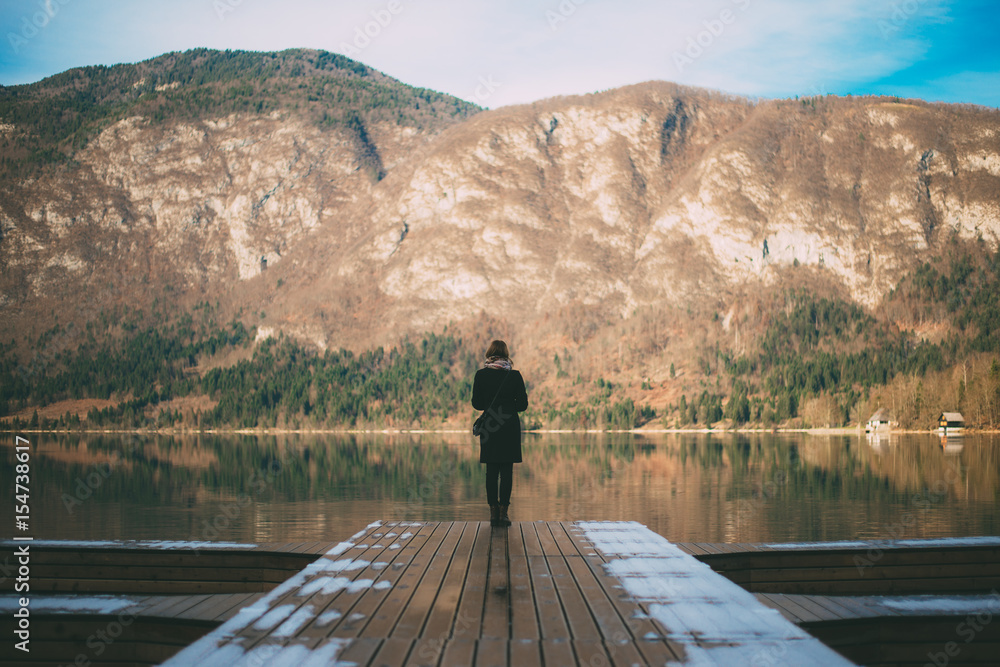 Girl standing near lake and looking at mountains