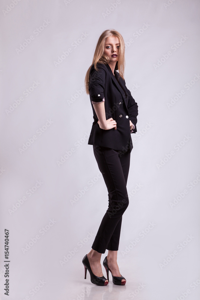Styled sexy woman in fashion suit on gray background in studio photo. Elegant blonde Styled sexy woman in fashion suit on gray background in studio photo. Elegant blonde