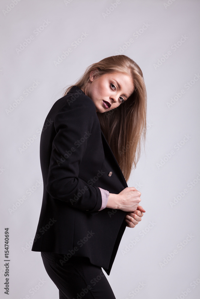 Styled sexy woman in fashion suit on gray background in studio photo. Elegant blonde Styled sexy woman in fashion suit on gray background in studio photo. Elegant blonde