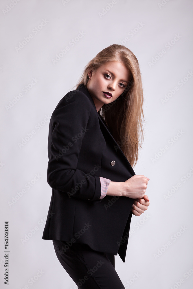 Styled sensual woman in fashion suit on gray background in studio photo. Elegant blonde Styled sensual woman in fashion suit on gray background in studio photo. Elegant blonde