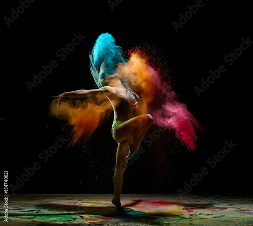 Girl dancing in a cloud of color dust studio portrait