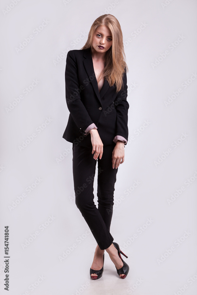 Styled gorgeous woman in fashion suit on gray background in studio photo. Elegant blonde Styled gorgeous woman in fashion suit on gray background in studio photo. Elegant blonde