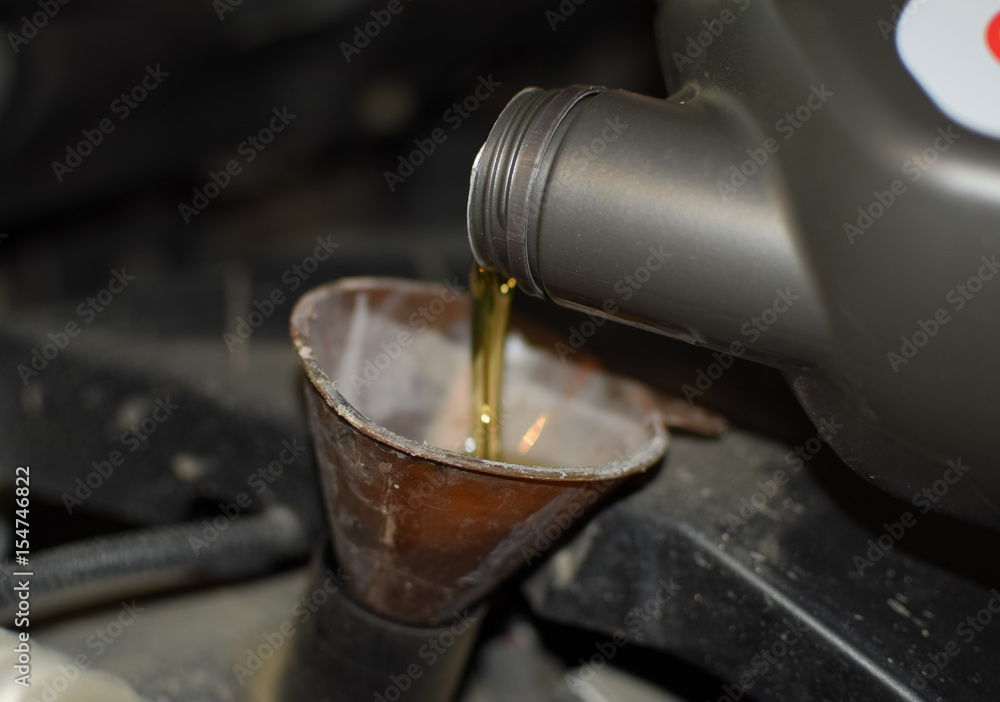 Oil change in the engine of the car. Filling the oil through the funnel. Car maintenance station. Oil change in the engine of the car. Filling the oil through the funnel. Car maintenance station.