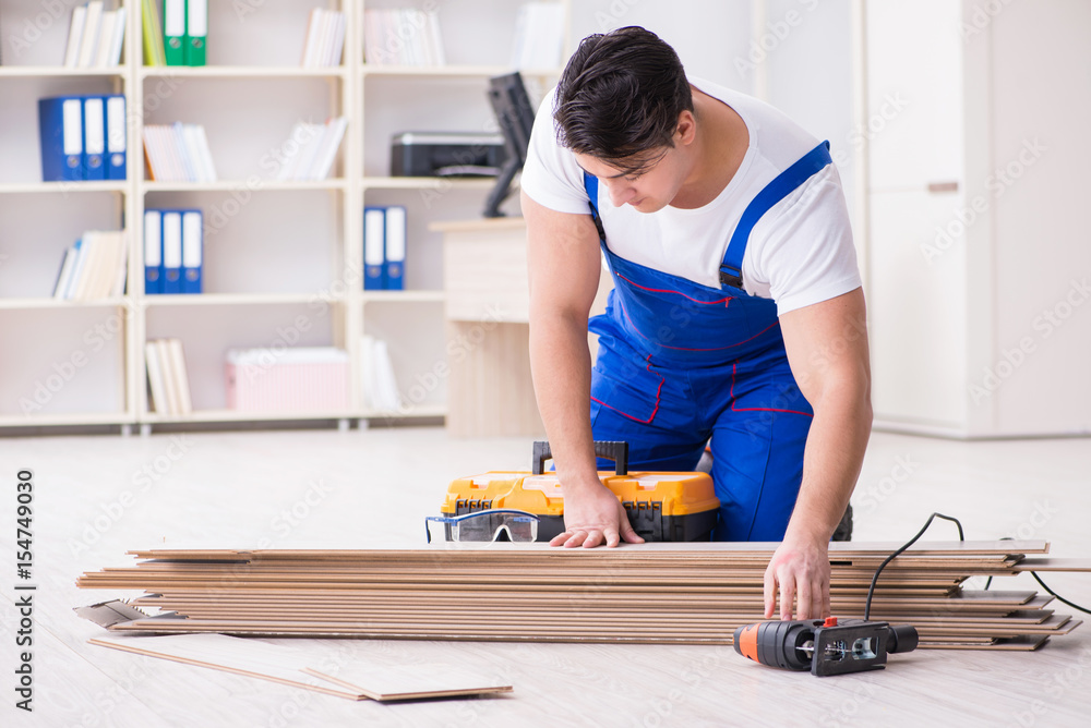 Young worker working on floor laminate tiles Young worker working on floor laminate tiles