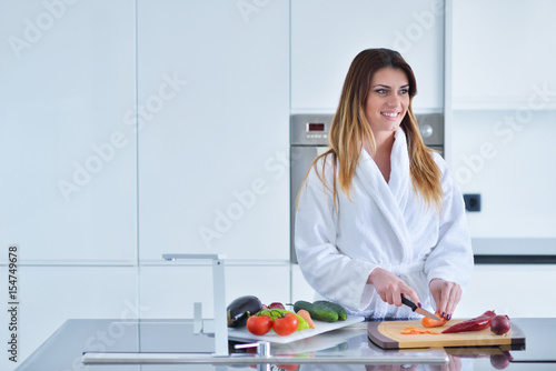 Smiling beautiful woman preparing salad at morning breakfast. Photo of young woman in bathrobe. Diet. Healthy lifestyle