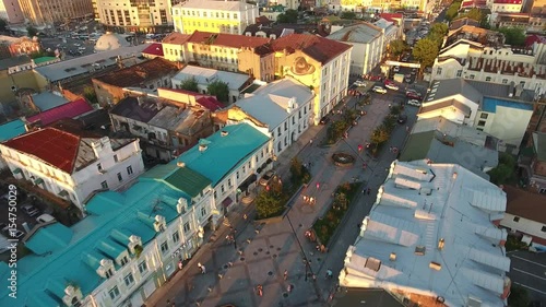 Flight above old small brick houses walking street. Vladivostok Russia Millionka district. Beautiful summer evening sunset. Long shadows. Rooftops mansards. Aerial drone 4k footage. People pedestrian  photo