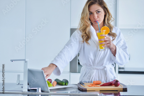 Smiling beautiful woman preparing salad at morning breakfast. Photo of young woman in bathrobe. Diet. Healthy lifestyle photo