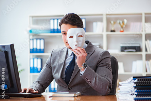 Businessman with mask in office hypocrisy concept photo