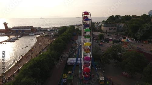 Sportivnaya embankment people walking street near the sea. Vladivostok Russia. Sunset reflection in the ocean. Warm sunset. Beach center of the city. Aerial drone flight around Ferris wheel photo