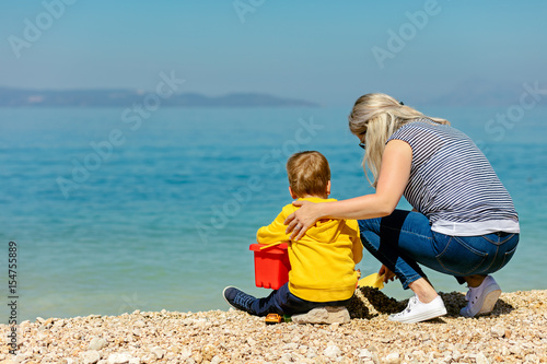 A happy mother and young child boy son having fun on a sunny beach