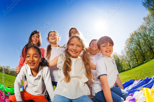 Happy kids sitting together on lawn at sunny day