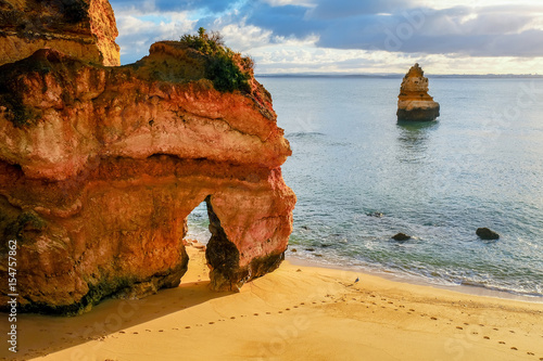 beautiful Atlantic ocean view horizon with sandy beach,  rocks and waves at sunrise. Algarve,  Portugal