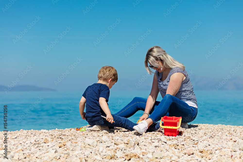 A happy mother and young child boy son having fun on a sunny beach A happy mother and young child boy son having fun on a sunny beach