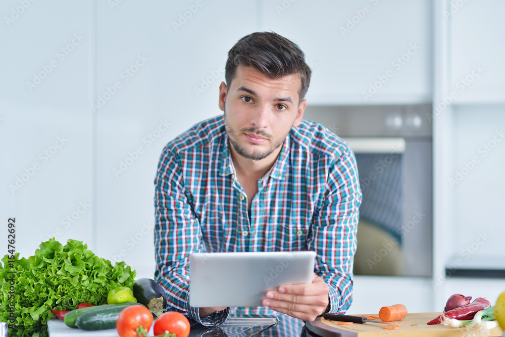 Happy man using digital tablet in kitchen at home Happy man using digital tablet in kitchen at home