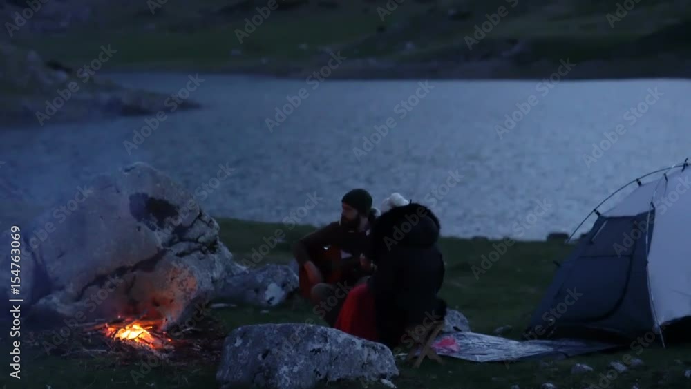 Couple of travelers at dusk near a campfire Couple of travelers at dusk near a campfire