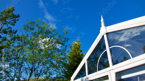 Εκτύπωση καμβά Blue sky, trees and clouds reflected in a garden conservatory.
