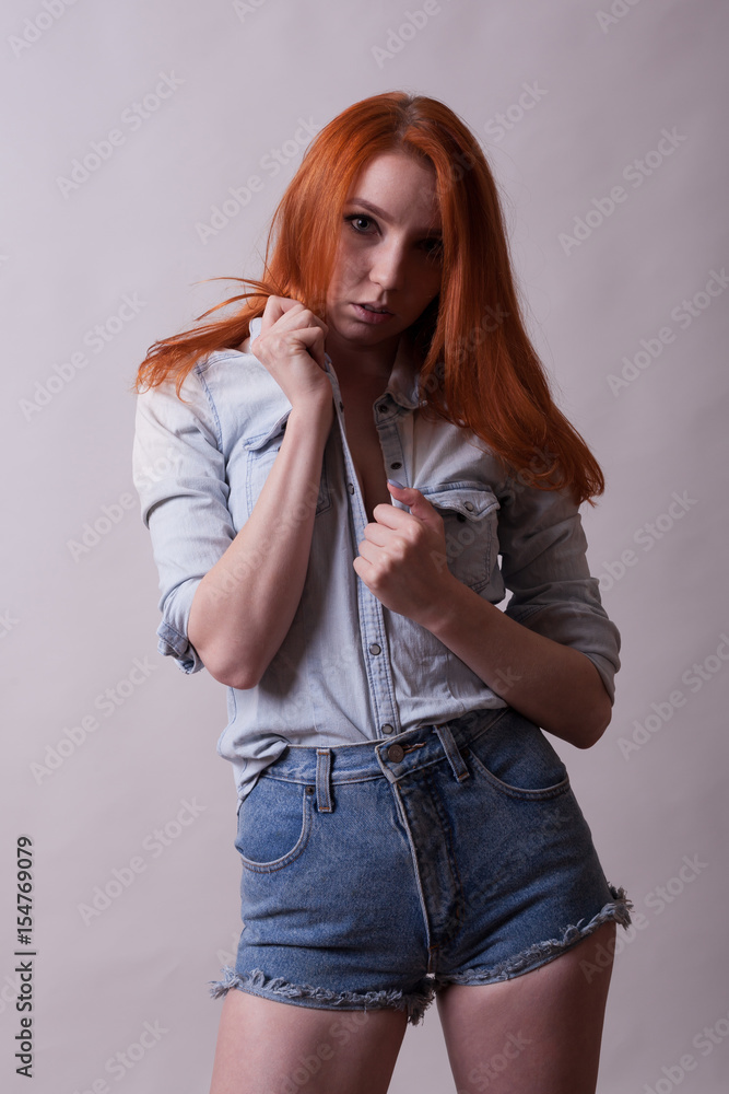 Beautiful busty woman in short and jeans shirt in studio photo on gray  background. Sexuality and sensuality. Attractive model Stock Photo | Adobe  Stock