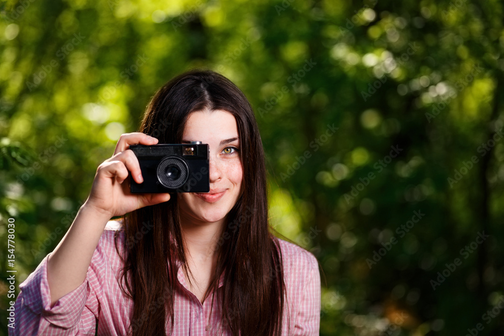 Young beautiful girl taking photos with retro film camera in the park Young beautiful girl taking photos with retro film camera in the park
