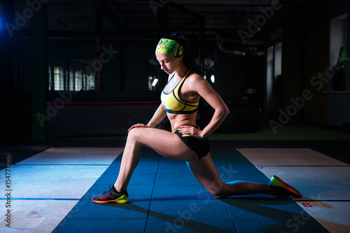 beautiful, strong, slender, in good physical shape in the gym doing exercises. Dressed in short shorts and tank top green, on the head bandage.