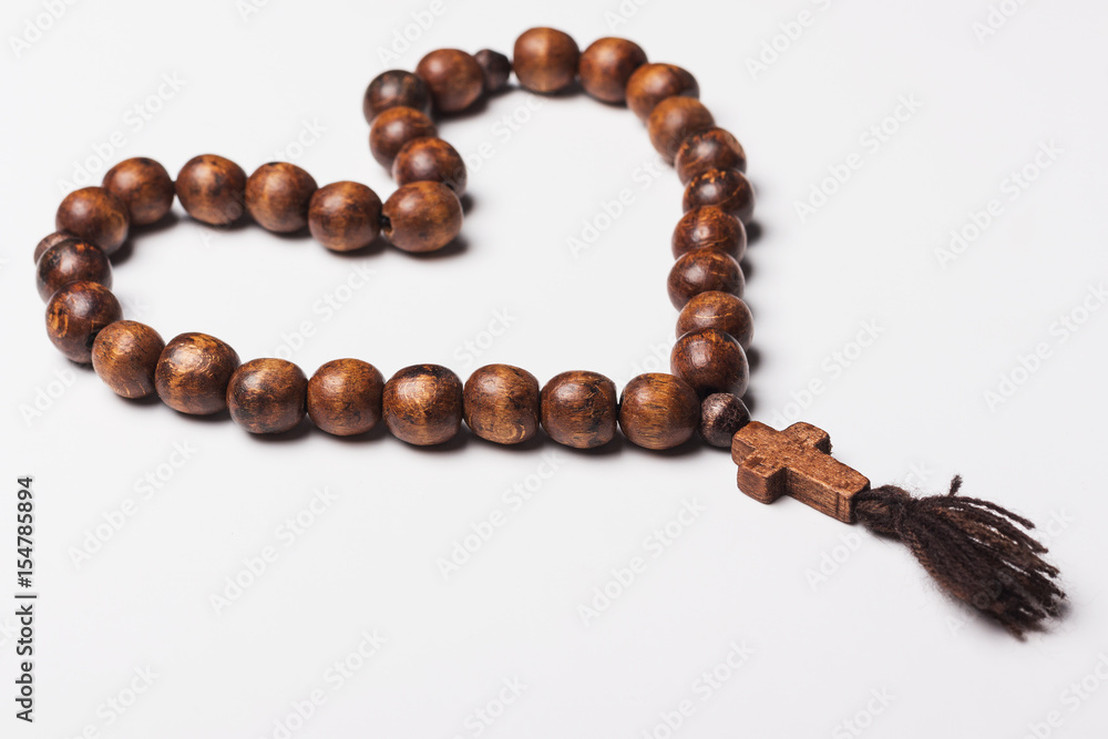 Rosary and a cross on a light gray background. in the shape of a heart Rosary and a cross on a light gray background. in the shape of a heart