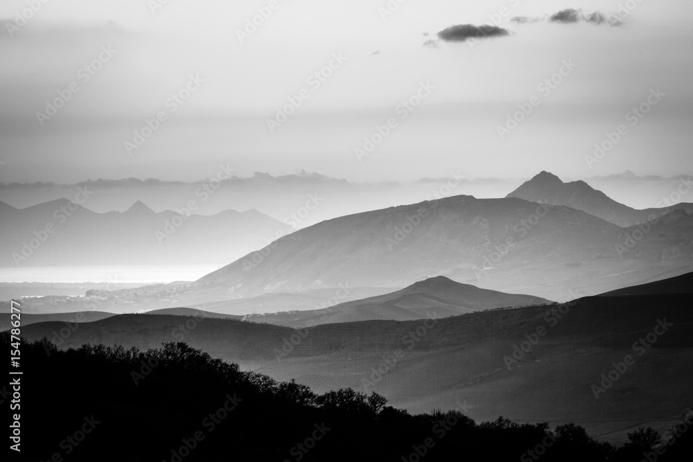 Fototapeta Czarno-biały panoramiczny widok mglisty krajobraz górski i sylwetki. Ficuzza, Sycylia, Włochy