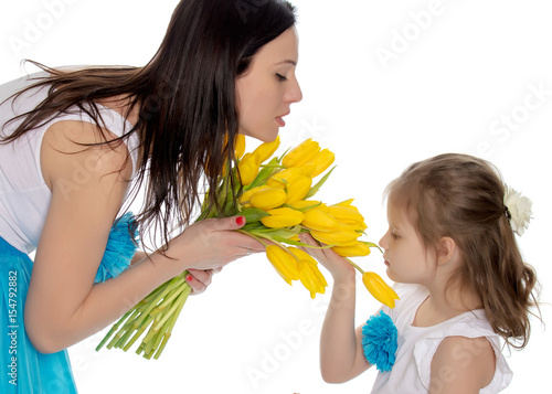 Mom and daughter enjoying the fragrance of flowers.