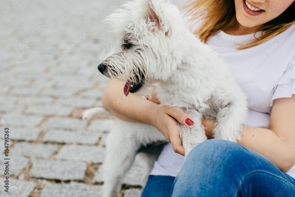 Beautiful young woman playing with her little west highland white terrier in a park outdoors. Lifestyle portrait. Beautiful young woman playing with her little west highland white terrier in a park outdoors. Lifestyle portrait.