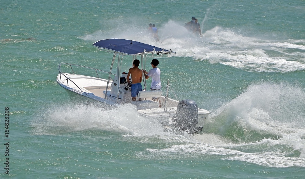 Obraz premium Fishing boat and jet skiers,week-end boat traffic on the florida intra-coastal waterway near miami beach.